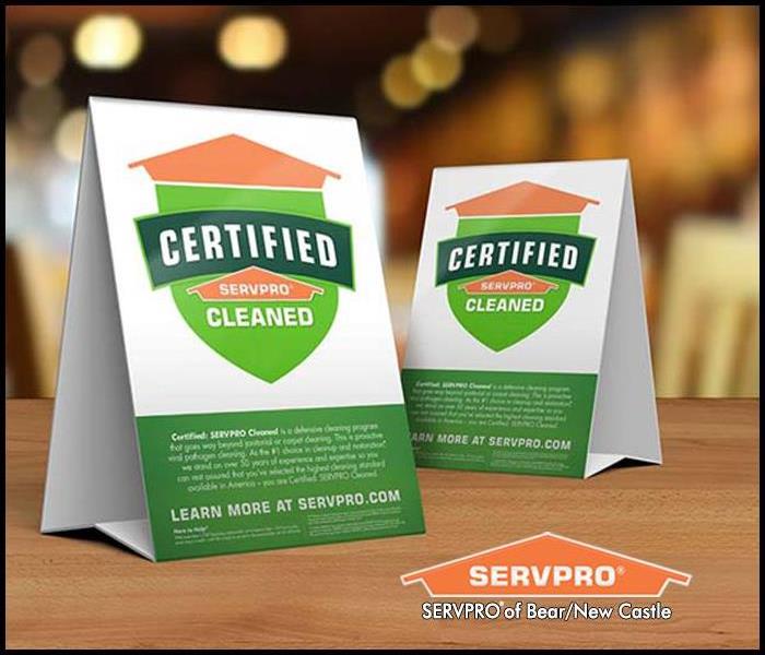 Table tent signs describing the Certified: SERVPRO Cleaned program on top of a wooden table. Body: