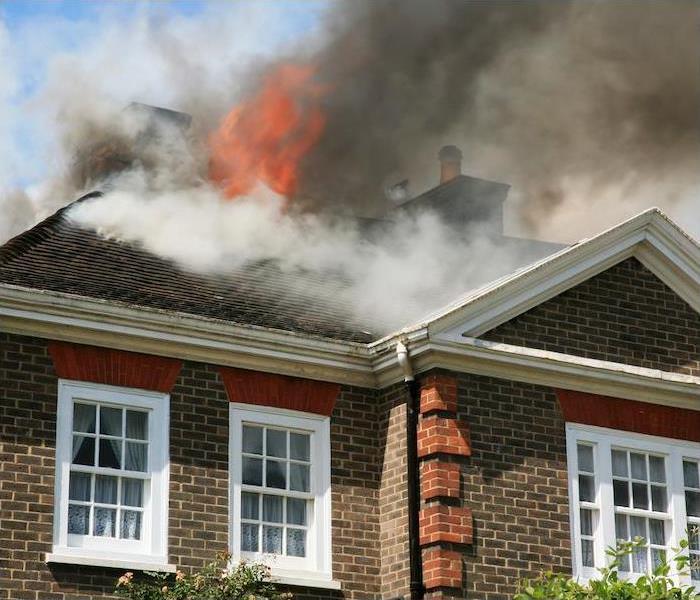 Fire and smoke billowing out of the roof of a brick two story home